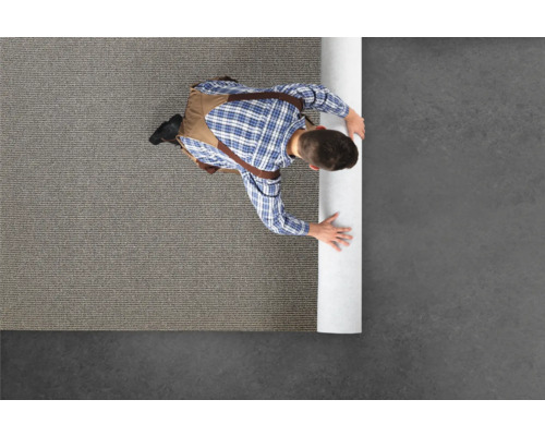 Een man legt vloerbedekking in een kamer.