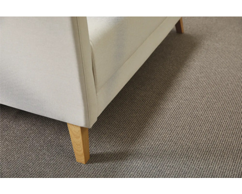 Detailopname van een beige tapijtvloer onder een bank met houten poten