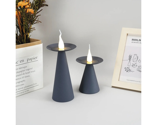 Twee grijze LED-kaarslampen op een tafel, decoratieve elementen op de achtergrond