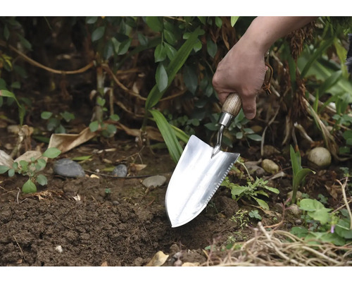 Tuinman plant met een plantschop in de tuin.