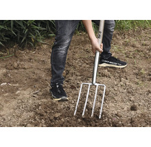 Persoon gebruikt een riek in de tuin.