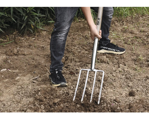 Persoon gebruikt een riek in de tuin.