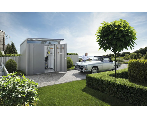 Tuinscene met gereedschapsschuur, oldtimer en persoon die de auto onderhoudt