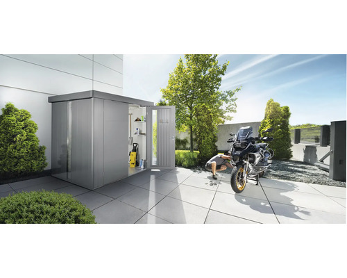 Metalen tuinhuis met open deur en motorfiets op een terras