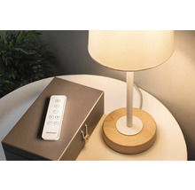 Lamp met houten voet, afstandsbediening en een decoratieve doos op een tafel