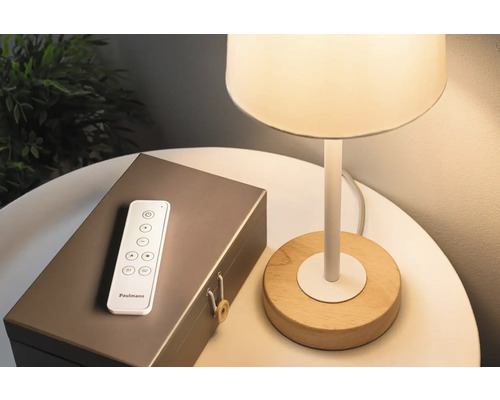 Lamp met houten voet, afstandsbediening en een decoratieve doos op een tafel