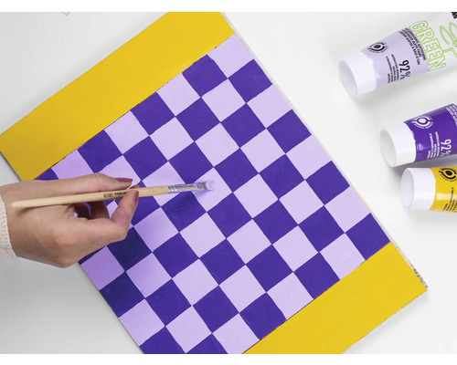 Persoon schildert schaakbordpatroon met penseel en verf