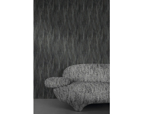 Grijze structuurbehang met bijpassende sofa op de achtergrond