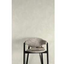 Stoel met stoffen bekleding, boeken en kom voor een muur