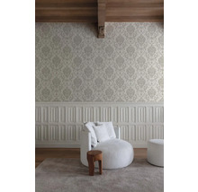 Woonkamer met patroonbehang, gestoffeerde fauteuil en houten kruk