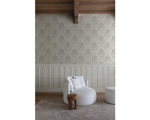 Woonkamer met patroonbehang, gestoffeerde fauteuil en houten kruk