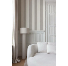 Interieurfoto van een kamer met gestreept behang, een staande lamp en een bank.