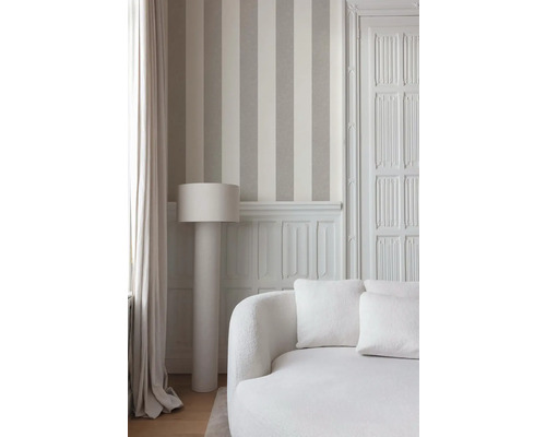 Interieurfoto van een kamer met gestreept behang, een staande lamp en een bank.