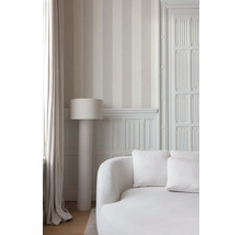 Lichte kamer met gestreept behang, een staande lamp en een sofa.