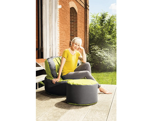 Vrouw zit op een grijze en limoengroene zitzak met voetenbank buiten