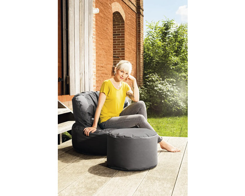 Vrouw ontspant op een grijze zitzak met kruk buiten