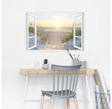 Muursticker met uitzicht vanuit het raam op een strand, bureau met kantoorbenodigdheden en stoel op de voorgrond