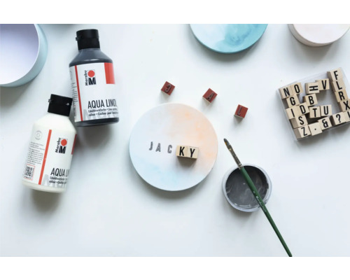 Scene met Marabu Aqua lino drukinkt, penseel, stempels en beschilderd rond canvas met de naam Jacky