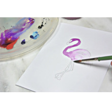 Aquarelschilderij van een flamingo op papier met penseel en palet