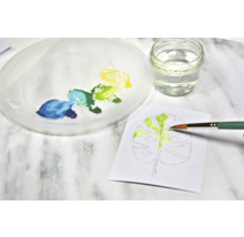 Aquarelschilderij van een blad met penseel, verf, water en palet