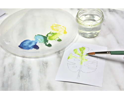 Aquarelschilderij van een blad met penseel, verf, water en palet