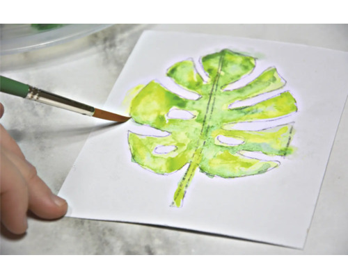 Aquarelschilderij van een Monstera blad met penseel op papier