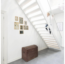 Wit trappenhuis met houten trap, kist en fotolijsten