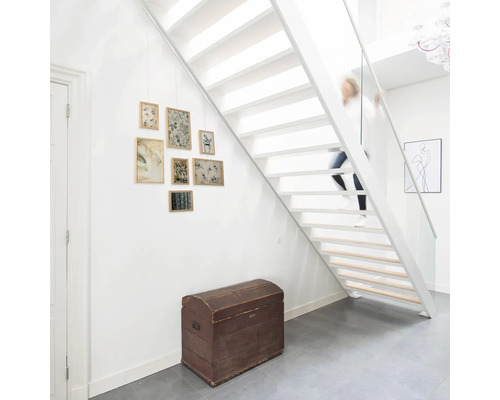 Wit trappenhuis met houten trap, kist en fotolijsten