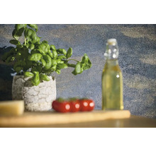 Stilleven met basilicumplant in een pot, tomaten en een fles olie op een houten tafel.