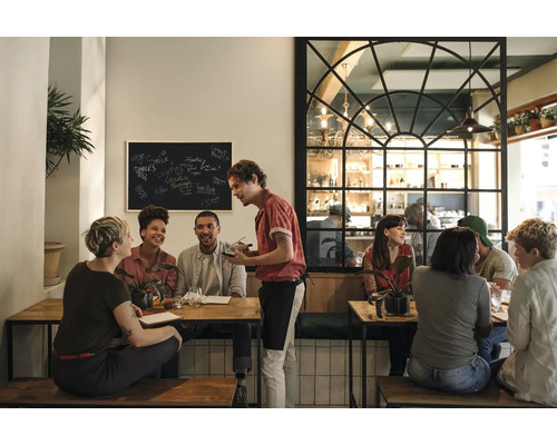 Scène in een restaurant met gasten aan tafels en een ober die bestellingen opneemt.