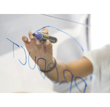 Een hand schrijft met een whiteboardstift op een glazen oppervlak.