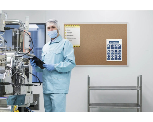 Man in beschermende kleding met tablet voor veiligheidsinformatie in cleanroom