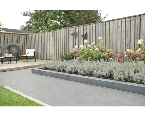 Aangelegde tuin met plantenperk, houten schutting en tuinmeubilair