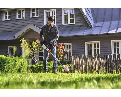 Man gebruikt een draadloze trimmer in de tuin.