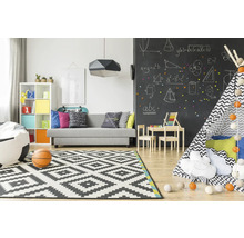 Lichte kinderkamer met bank, speelgoed, vloerkleed en schoolbordmuur