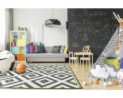 Lichte kinderkamer met bank, speelgoed, vloerkleed en schoolbordmuur