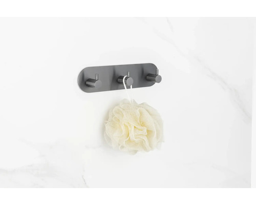 Wandkapstok met drie haken en badspons aan een badkamermuur