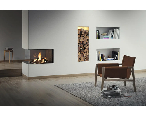 Woonkamer met open haard, houtblokken, boekenkasten en fauteuil op vloerkleed