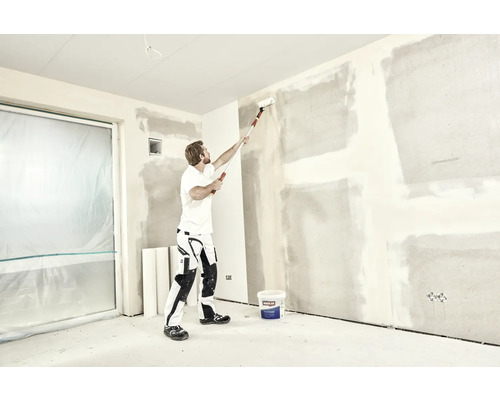 Man schildert muur met verfroller in een kamer, renovatieproject