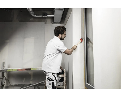 Man schildert muur met kwast op een bouwplaats