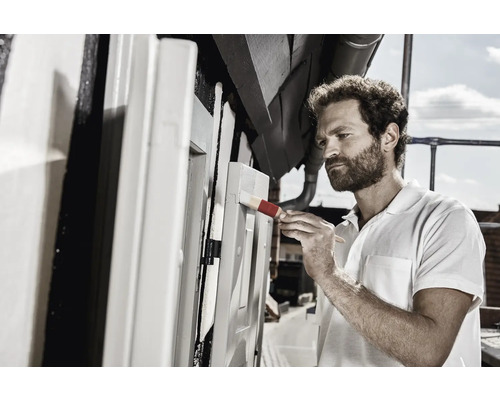 Man schildert met penseel houten constructie buitenshuis