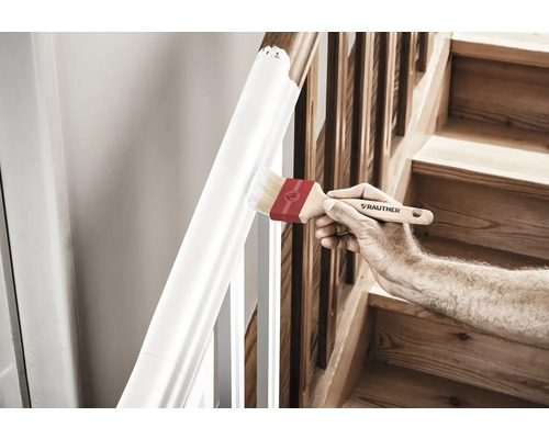 Een persoon schildert een trapleuning met een kwast.