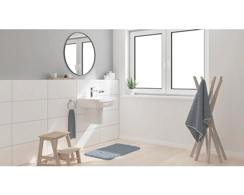 Lichte badkamer met wastafel, spiegel, handdoekrek en badmat