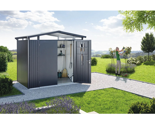 Tuinscene met tuinhuis, tuingereedschap en een vrouw die in de tuin werkt.