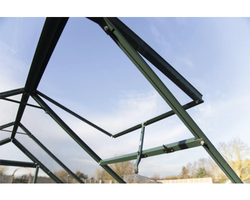 Groene kas in aanbouw, interieurbeeld van de frameconstructie tegen een blauwe lucht.