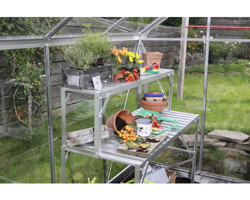 Kweekkas met plantentafel en tuingereedschap