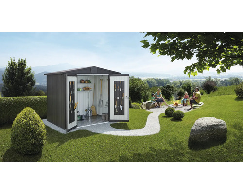 Tuinscene met een metalen tuinhuis met open deuren, waarin tuingereedschap wordt bewaard, en een gezin dat ontspant bij een kampvuur