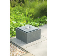 Fontein van steen met waterspel in de tuin