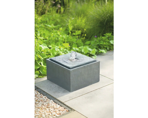 Fontein van steen met waterspel in de tuin