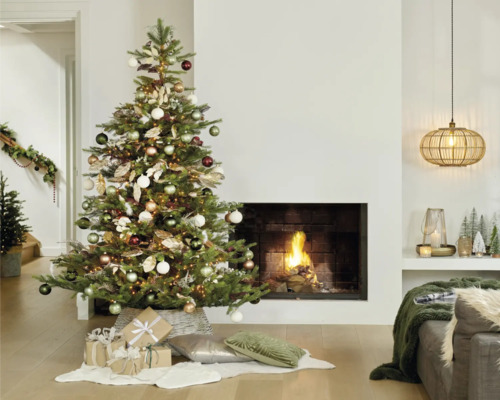 Kerstboom versierd met ballen en cadeaus in de woonkamer met open haard.